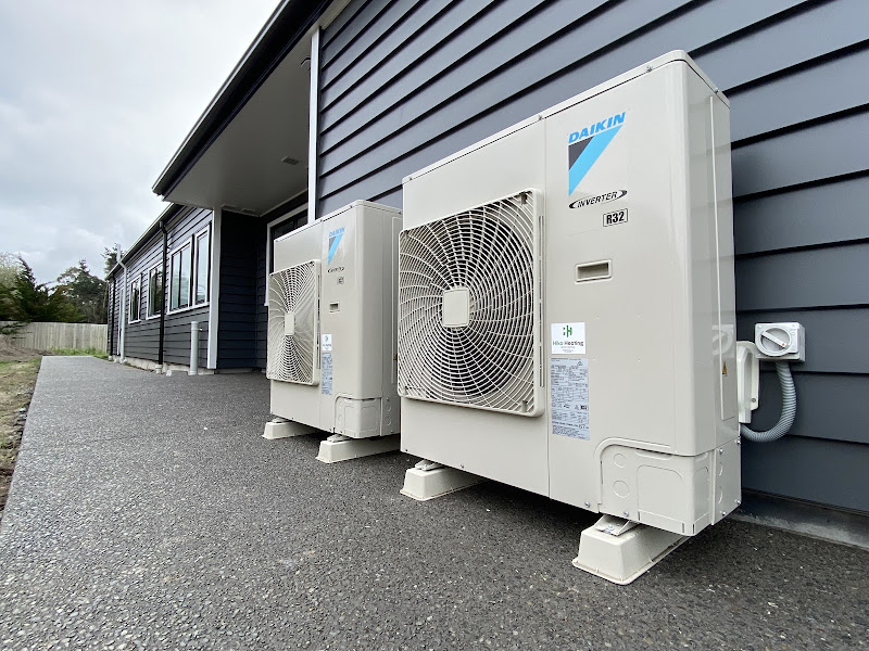 Two Daikin heat pump outdoor units installed by Hiko Heating and Electrical beside a dark-clad Christchurch home