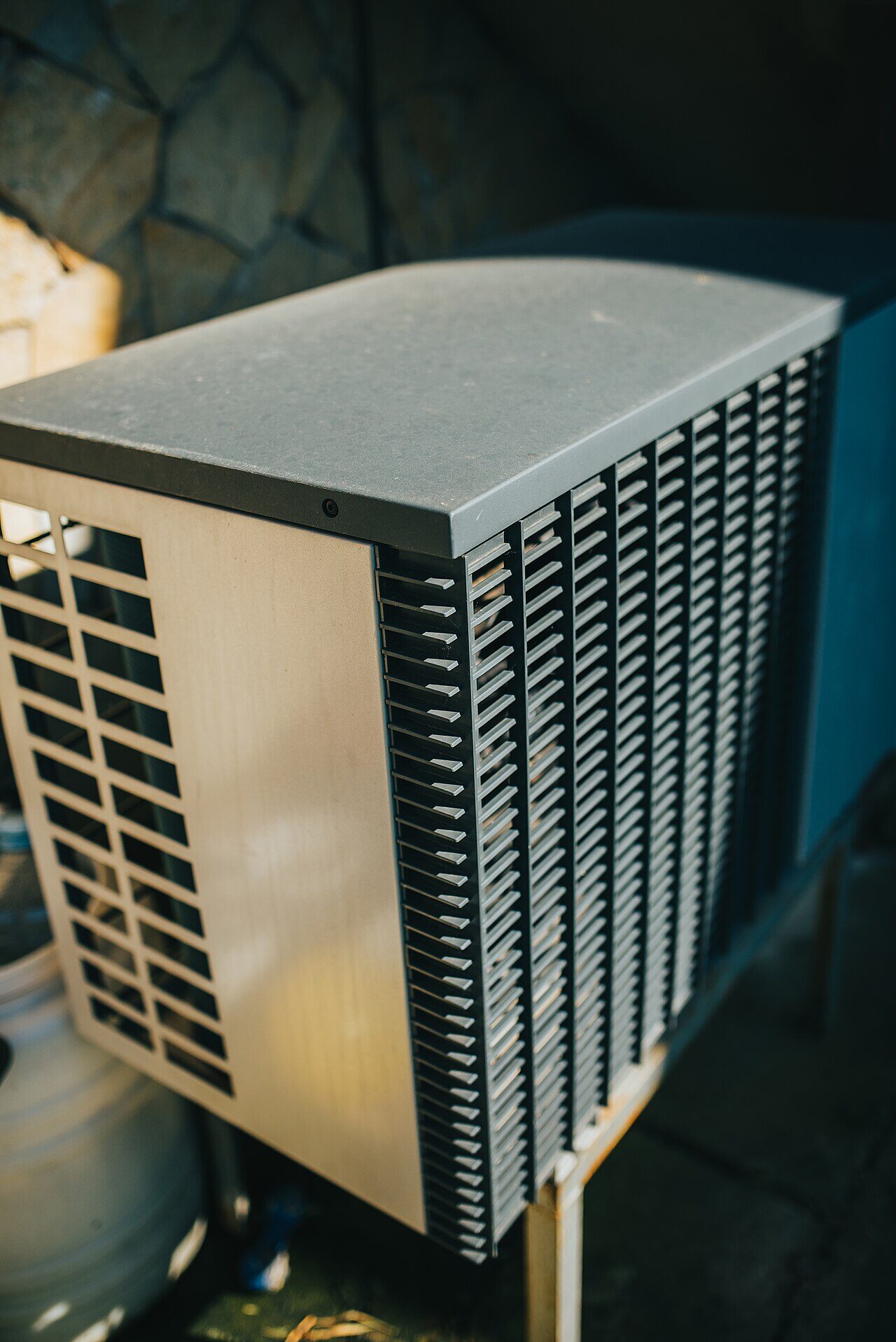 Close-up of a heat pump outdoor unit installed in a residential garden bed