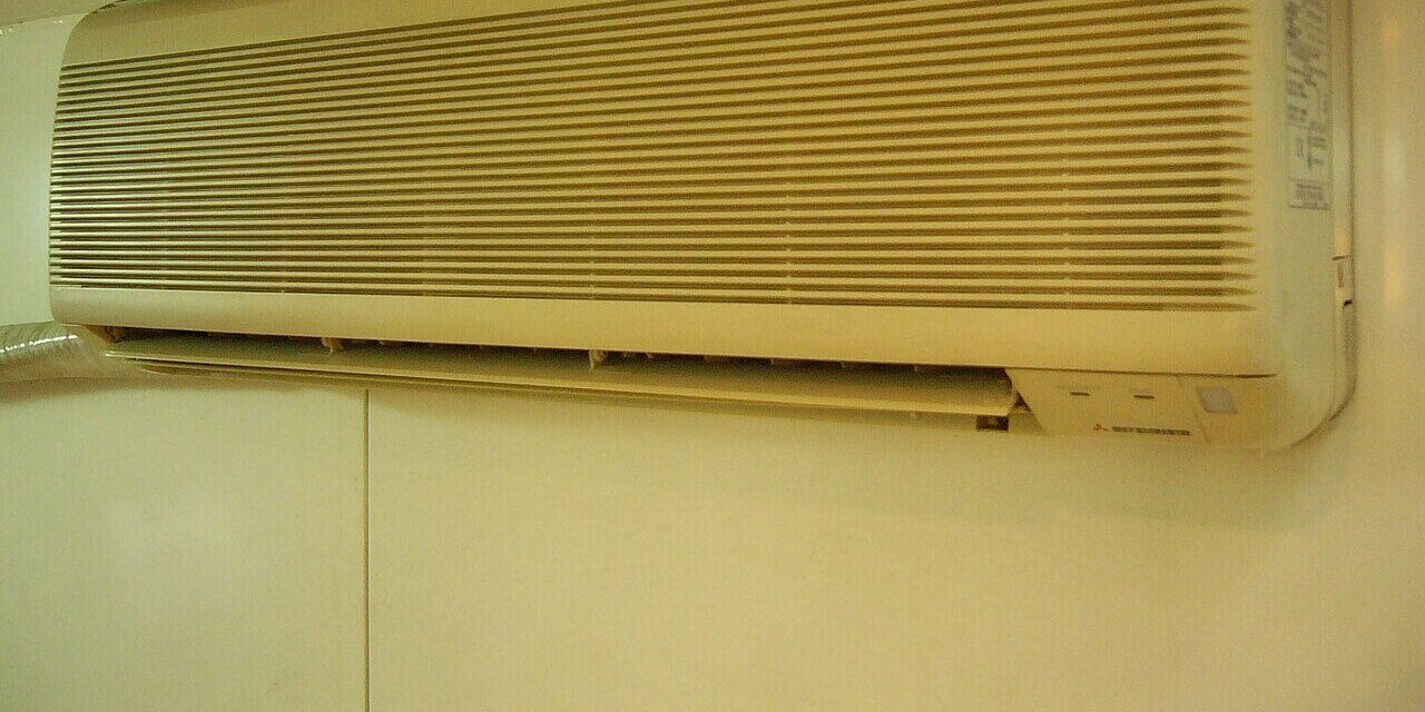 Mitsubishi wall-mounted indoor heat pump head unit on a living room wall